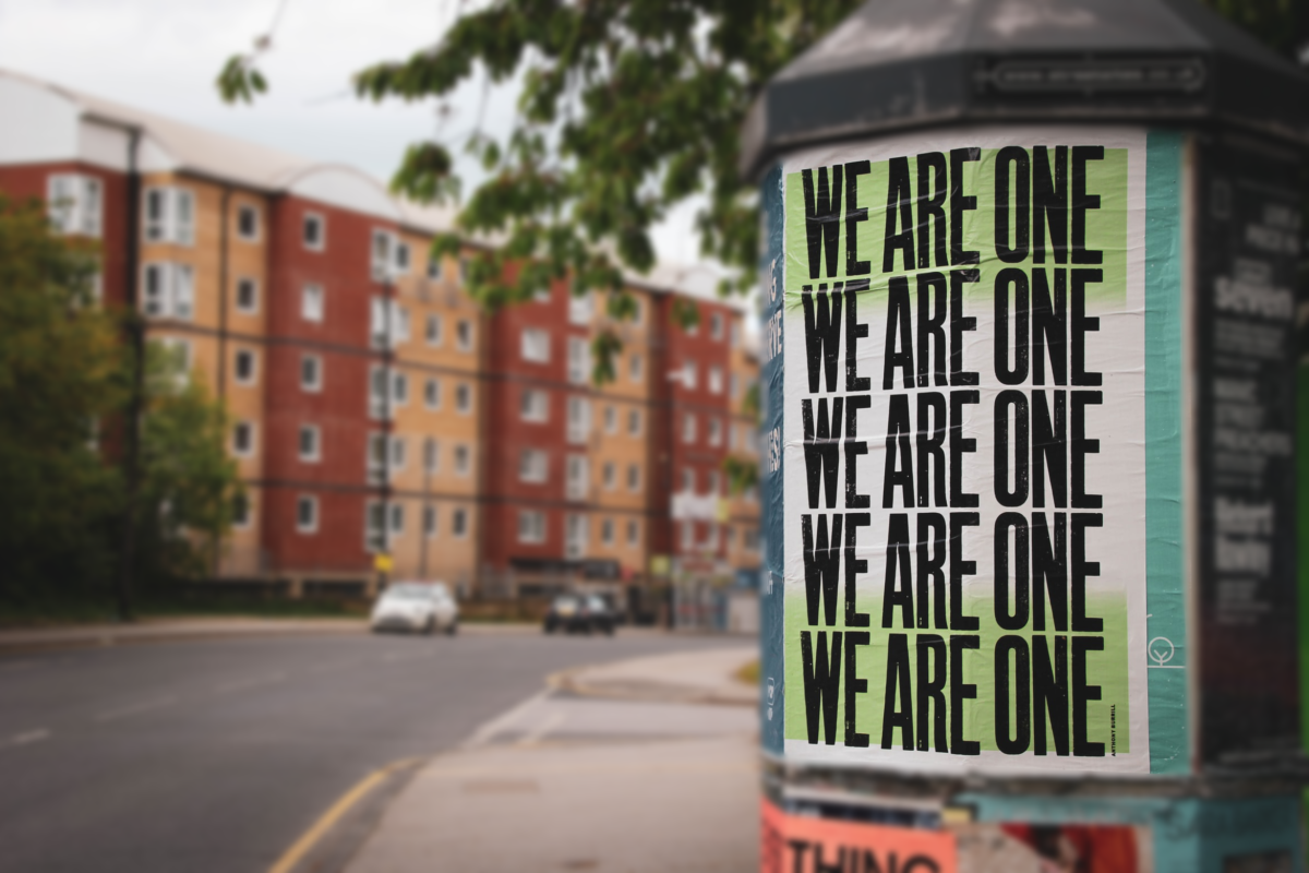 A poster saying "We are one" with a building in the background.
